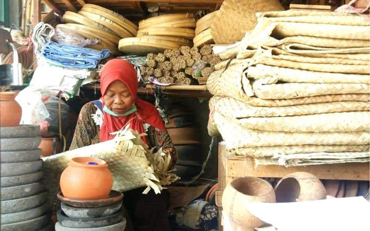 Seorang pedagang alat rumah tangga tradisional sedang menunggui dagangannya sambil menganyam di pasar tradisional Desa Gabus, Kecamatan Gabus, Pati, Jawa tengah,  Sabtu (7/9/2019). Hingga saat ini penjualan alat-alat rumah tangga tradisional berbahan baku bamboo, tanah liat dan kayu masih bertahan.