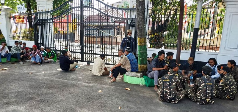 Sejumlah warga Desa Kedungwinong duduk-duduk di halaman kantor Pemkab Pati. Mereka hendak mengikuti pertemuan soal kasus rehab halaman masjid namun peserta dibatasi, Selasa (3/8/2021) / Clakclik.com 